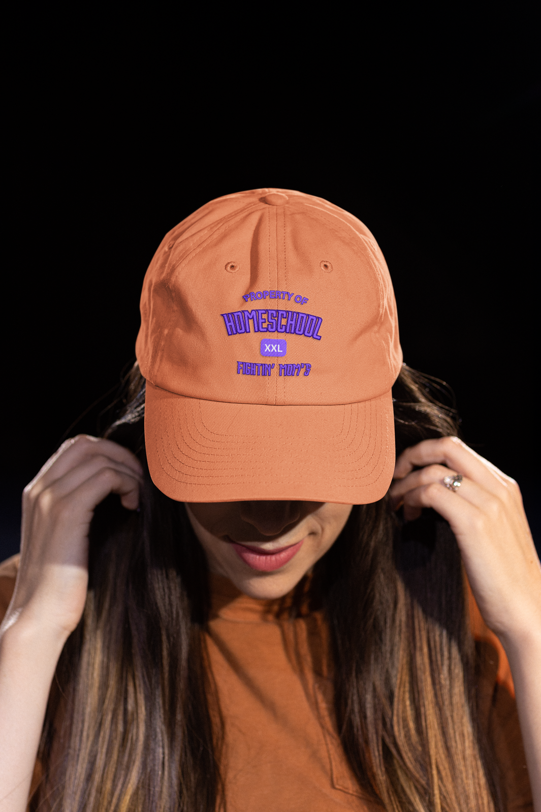 a woman sporting a orange hat with the caption of property of homeschool fighing mom's