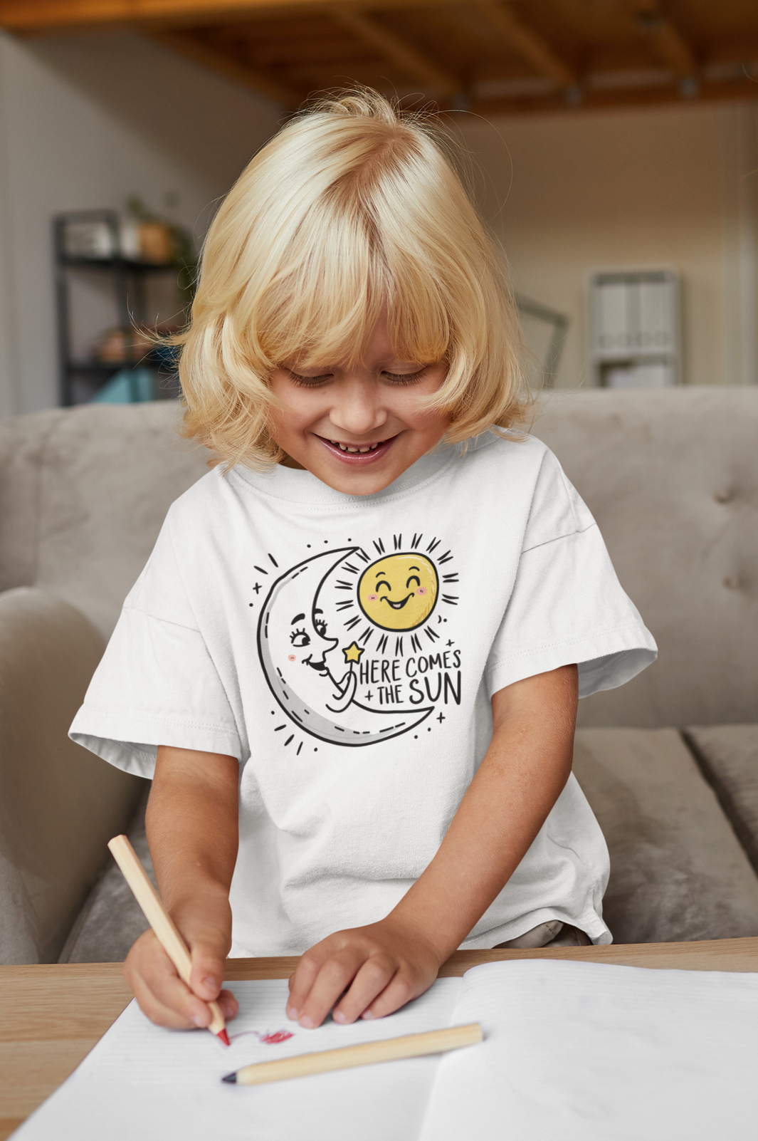 A youth shirt with the happy moon greeting the sun and the slogan here comes the sun